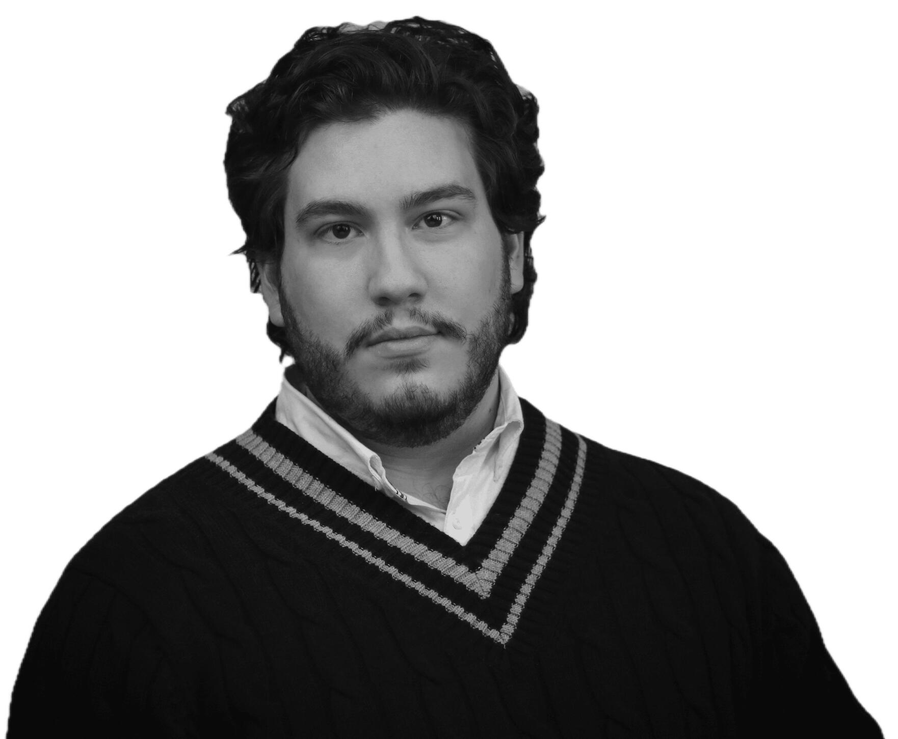 Headshot of Dennis Oliveira. Image of a brown eyed, brown haired, latino person in a white button down shirt and black sweater, against a Light Blue background.